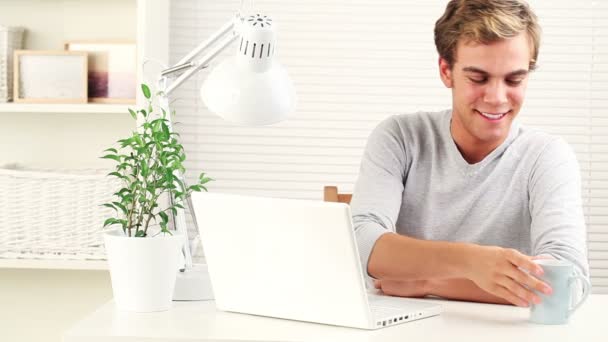 Joyful young university student using laptop drinking coffee — Stock Video