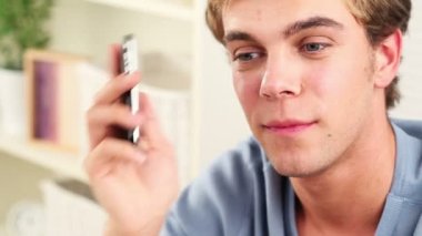 mutlu genç adam cep telefonuyla kısa mesaj gönderme