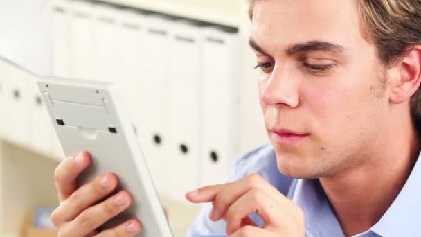 Atractivo hombre de negocios sosteniendo una calculadora y sonriendo — Vídeos de Stock