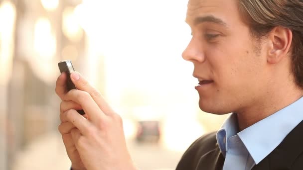 Aantrekkelijke jonge zakenman chatten op mobiele telefoon buitenshuis — Stockvideo