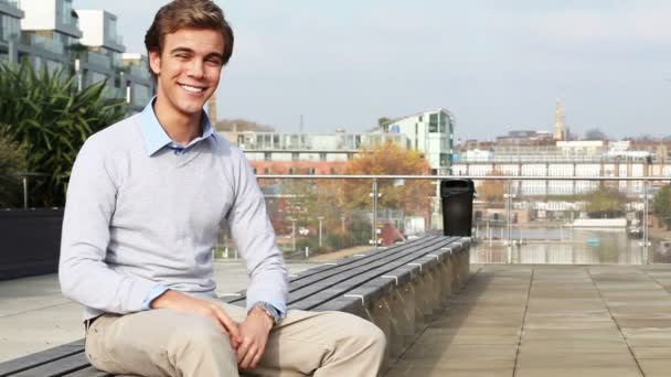 Atractivo joven sonriendo a la cámara al aire libre en la escena urbana de la ciudad — Vídeos de Stock