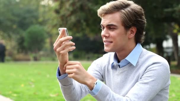 Happy young man using talking on mobile phone outdoors — Stock Video