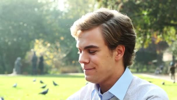 Gezonde goed uitziende jonge man drinkwater buiten in het zonnige park — Stockvideo