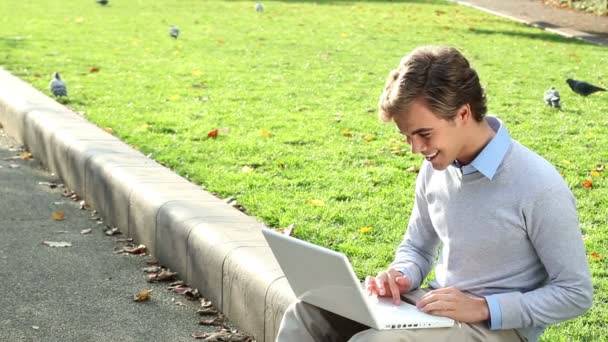 Aantrekkelijke jonge student is blij met laptop in park - buitenshuis — Stockvideo