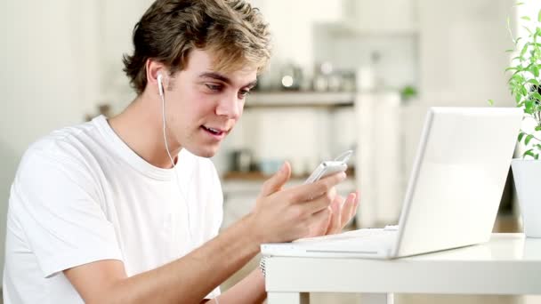 Bonito jovem estudante adolescente usando telefone celular e laptop em casa — Vídeo de Stock