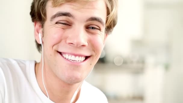 Крупный план портрета радостного молодого человека, слушающего музыку в помещении — стоковое видео