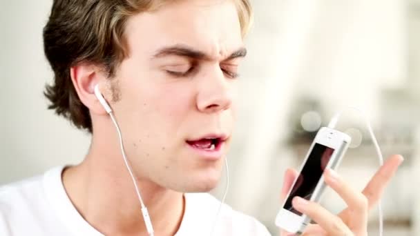 Close-up portrait of joyful young man listening to music - indoors — Stock Video