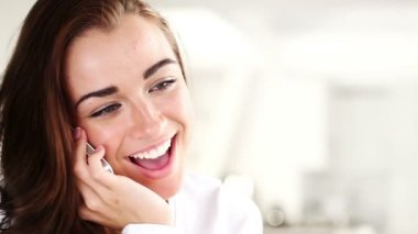Evde cep telefonuyla konuşan neşeli genç bir kadın.