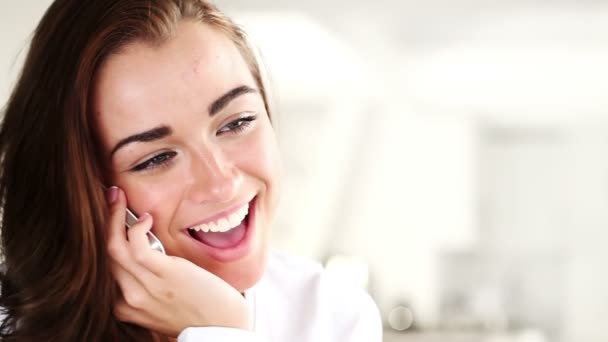 Radostná mladá žena mluví na mobilním telefonu doma