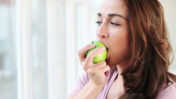 Крупный план портрета милой молодой женщины, поедающей яблоко — стоковое видео