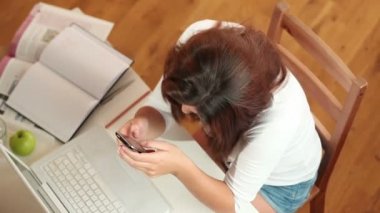 Evde cep telefonunu kullanan genç bir kadın.