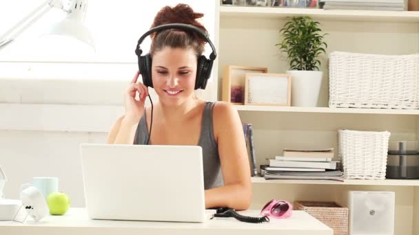 Young woman listening to music on a laptop at home — Stock Video
