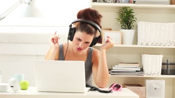 Jovem mulher ouvindo música em um laptop em casa — Vídeo de Stock