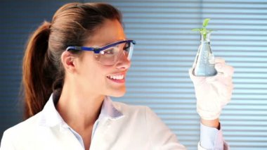 Laboratuarda gülümseyerek ve holding bir bitki duran öğrenci