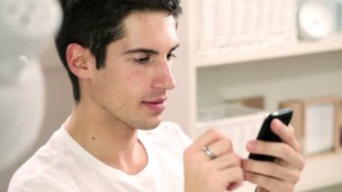 Genç yakışıklı adam cep telefonuna SMS yazıyor.