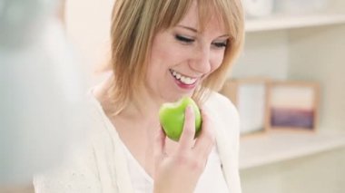 yeme elma ve gülümseyen genç kadındır