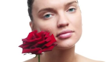 kadın beyaz bir arka plan üzerinde taze tek kırmızı gül çiçek tarafından yüzüne dokunmak