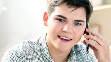 Genç adam evde telefonla konuşuyor.