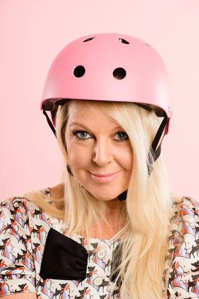 Bisiklet kaskı portre pembe arka plan gerçek giymiş komik kadın — Stok fotoğraf