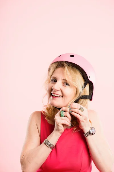 Mulher engraçada vestindo ciclismo capacete retrato rosa fundo real — Fotografia de Stock