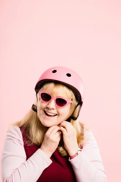 Mulher engraçada vestindo ciclismo capacete retrato rosa fundo real — Fotografia de Stock