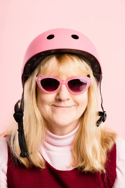 Mulher engraçada vestindo ciclismo capacete retrato rosa fundo real — Fotografia de Stock