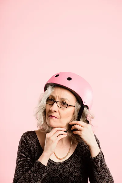 Mulher engraçada vestindo ciclismo capacete retrato rosa fundo real — Fotografia de Stock