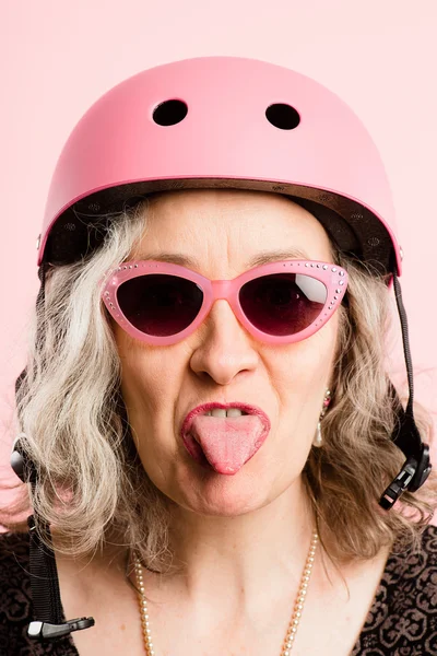 Mulher engraçada vestindo ciclismo capacete retrato rosa fundo — Fotografia de Stock