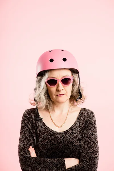 Mulher engraçada vestindo ciclismo capacete retrato rosa fundo — Fotografia de Stock