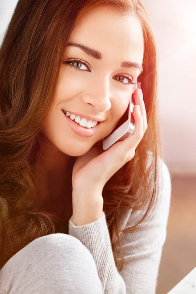 Pretty young woman using mobile phone at home — Stock Photo, Image