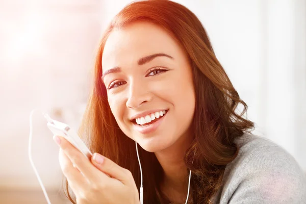 Mooie jonge vrouw met behulp van mobiele telefoon luisteren naar muziek — Stockfoto