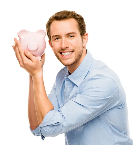Χαρούμενος νεαρός βάζοντας χρήματα στην Τράπεζα γουρουνάκι που απομονώνονται σε λευκό — Φωτογραφία Αρχείου