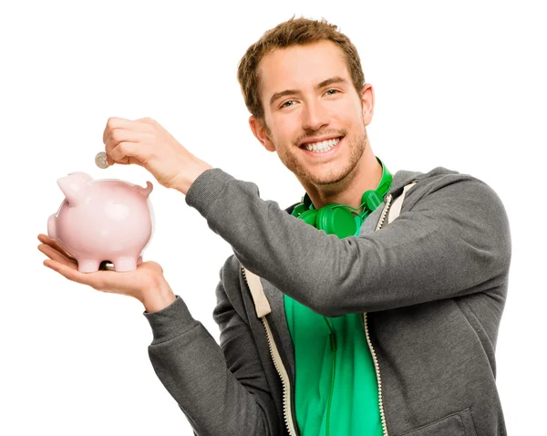 Happy young man putting money in piggy bank isolated on white — Stock Photo, Image