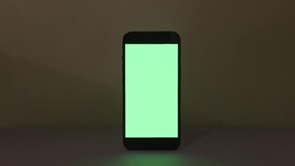 Close-up weergave van moderne smartphone met groen scherm op groene achtergrond, blanco scherm mockup — Stockvideo