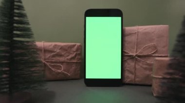 Dikey yönelimli cep telefonu. Arka planda Noel ağacı resmi ve el sanatları var. Çevrimiçi mağaza, uygulama tanıtımı, reklamlar. Görüntüyü yakınlaştır