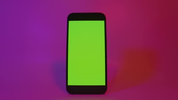 Cellulare iPhone 13 con schermo verde, smartphone mock up. Illuminazione di colore rosa e viola. Smartphone moderno a schermo piatto — Video Stock