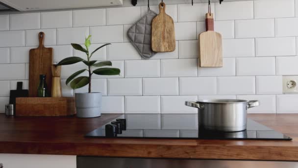 Ustensiles de cuisine en laiton, accessoires de cuisine.L'eau bout dans une casserole. Cuisine suspendue avec mur de tuiles blanches et table en bois.Plante verte sur fond de cuisine — Video