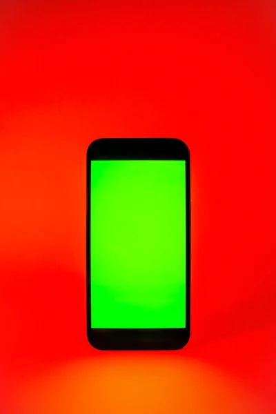 Mobile phone with green screen, smartphone mock up. Red illumination. Flat screen modern smartphone — стоковое фото