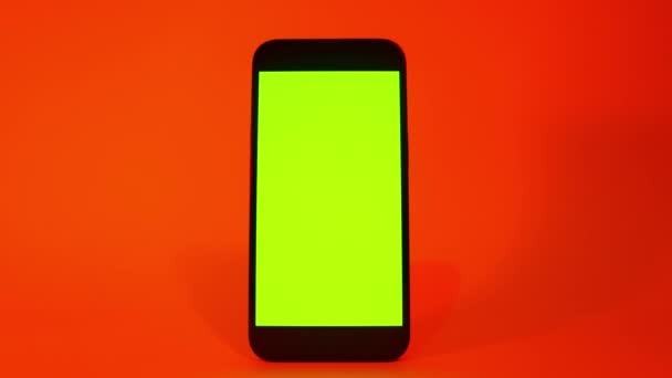 Cellulare con schermo verde, smartphone mock up. Illuminazione di colore rosso arancio. Smartphone moderno a schermo piatto — Video Stock