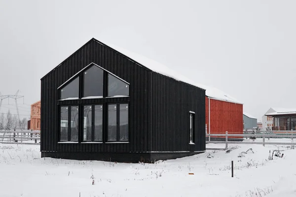 Casa de madera moderna en el estilo escandinavo con diferentes colores, día de invierno en el pueblo Imagen de archivo