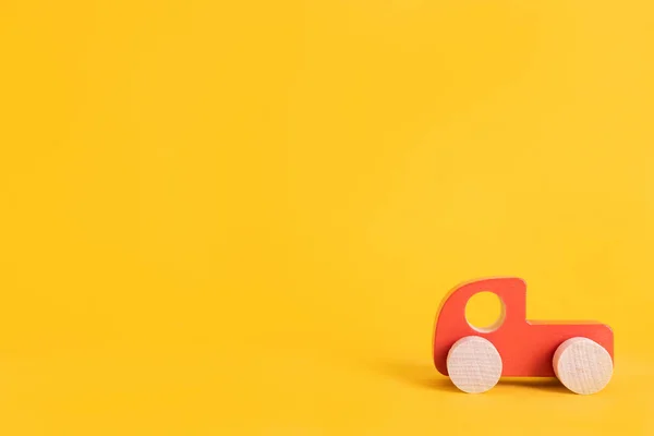 Coche de juguete de madera en estilo de dibujos animados sobre fondo amarillo. Fondo colorido y transporte, juguetes para niños ecológicos Montessori . Fotos de stock libres de derechos