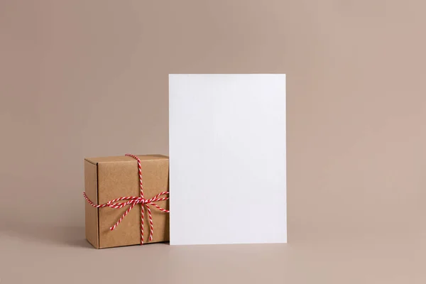 San Valentín, composición del día de la madre hecha de regalo con cinta roja y tarjeta blanca en blanco sobre fondo beige. Vista lateral, espacio de copia. —  Fotos de Stock