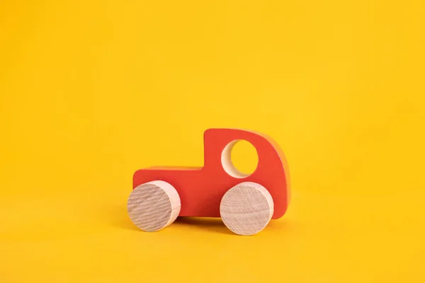 Ξύλινο παιχνίδι αυτοκίνητο σε στυλ κινουμένων σχεδίων σε κίτρινο φόντο. Πολύχρωμο και Μεταφορά φόντο, οικολογικά παιχνίδια παιδί Montessori . — Φωτογραφία Αρχείου
