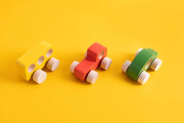 Coche de juguete de madera en estilo de dibujos animados sobre fondo amarillo. Fondo colorido y transporte, juguetes para niños ecológicos Montessori . Imágenes de stock libres de derechos