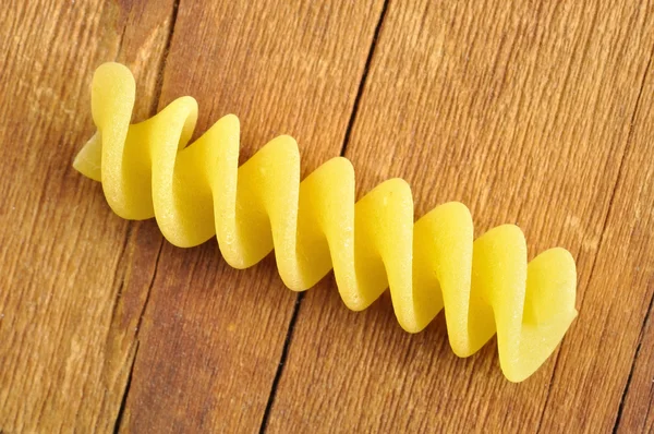 One fusilli pasta on a wooden chopping board, closeup — Stock Photo, Image