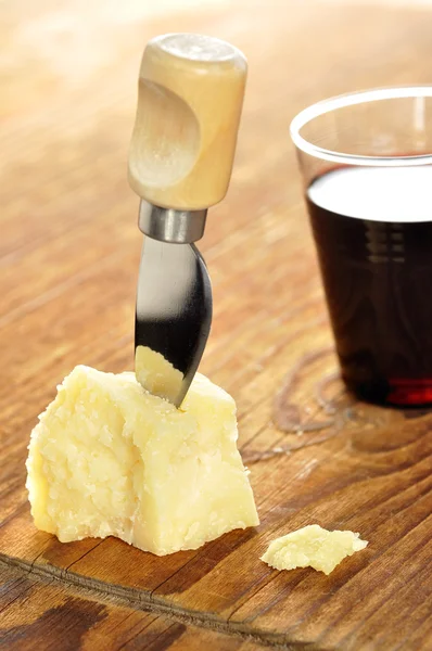 Parmigiano e bicchiere di vino rosso su un tagliere di legno — Foto Stock