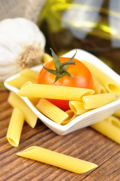 Raw penne pasta in a small bowl, selective focus — Stock Photo, Image