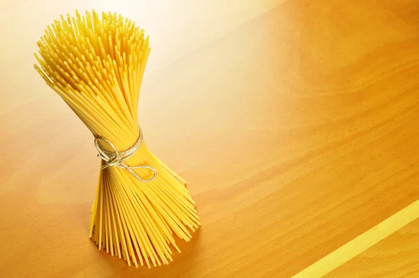 Pasta de espaguetis en una tabla de cortar de madera — Foto de Stock