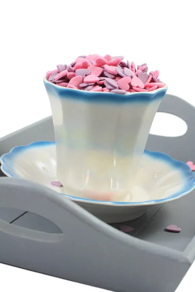 Corazones de caramelo en taza de café en bandeja gris aislado sobre blanco — Foto de Stock