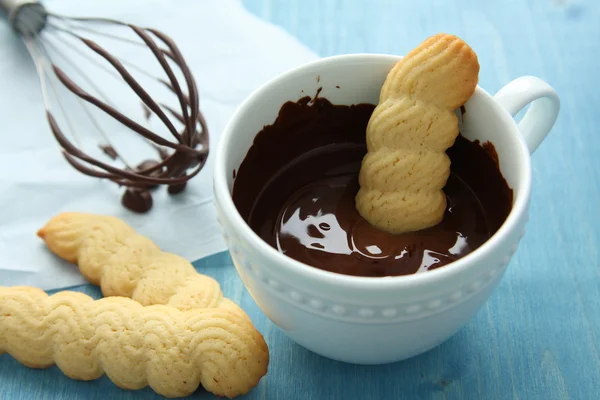 Cup of chocolate with shotrbread cookies and whisk